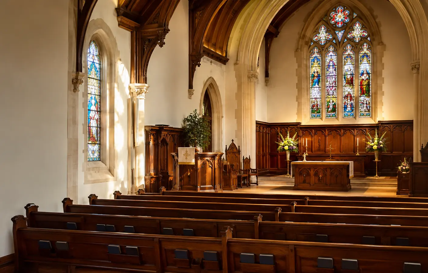 Warm, people-free historic church sanctuary with arched windows and orderly pews